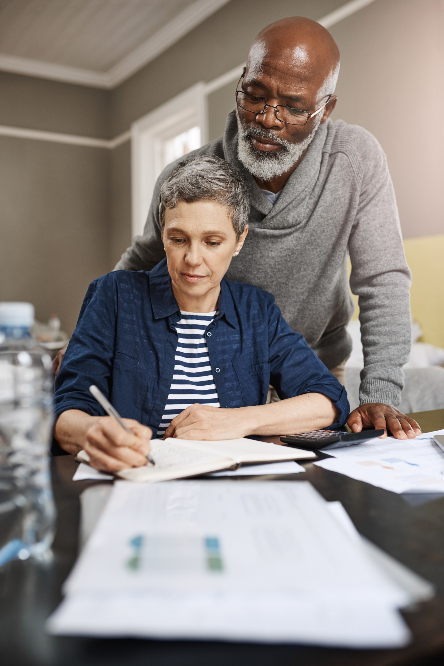 A Lady Signing Papers and a Man Looking Over Her | Reverse Mortgage Senior