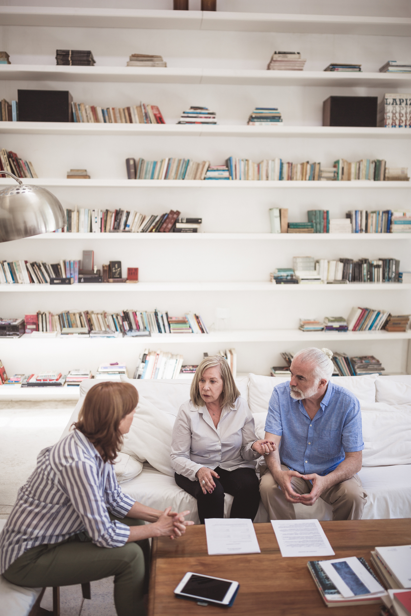 A Couple and a Woman Talking in a Room With a Huge Bookshelf | Reverse Mortgage Senior