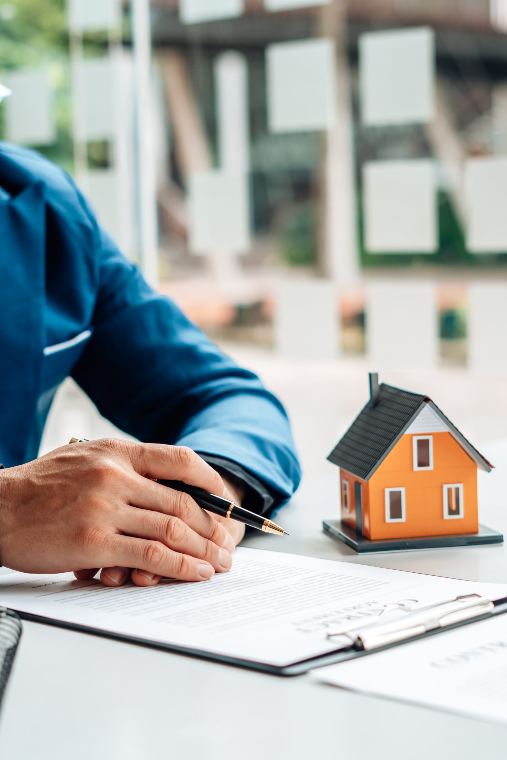 A Person With a Pen, Form, and a Miniature House | Reverse Mortgage FAQ